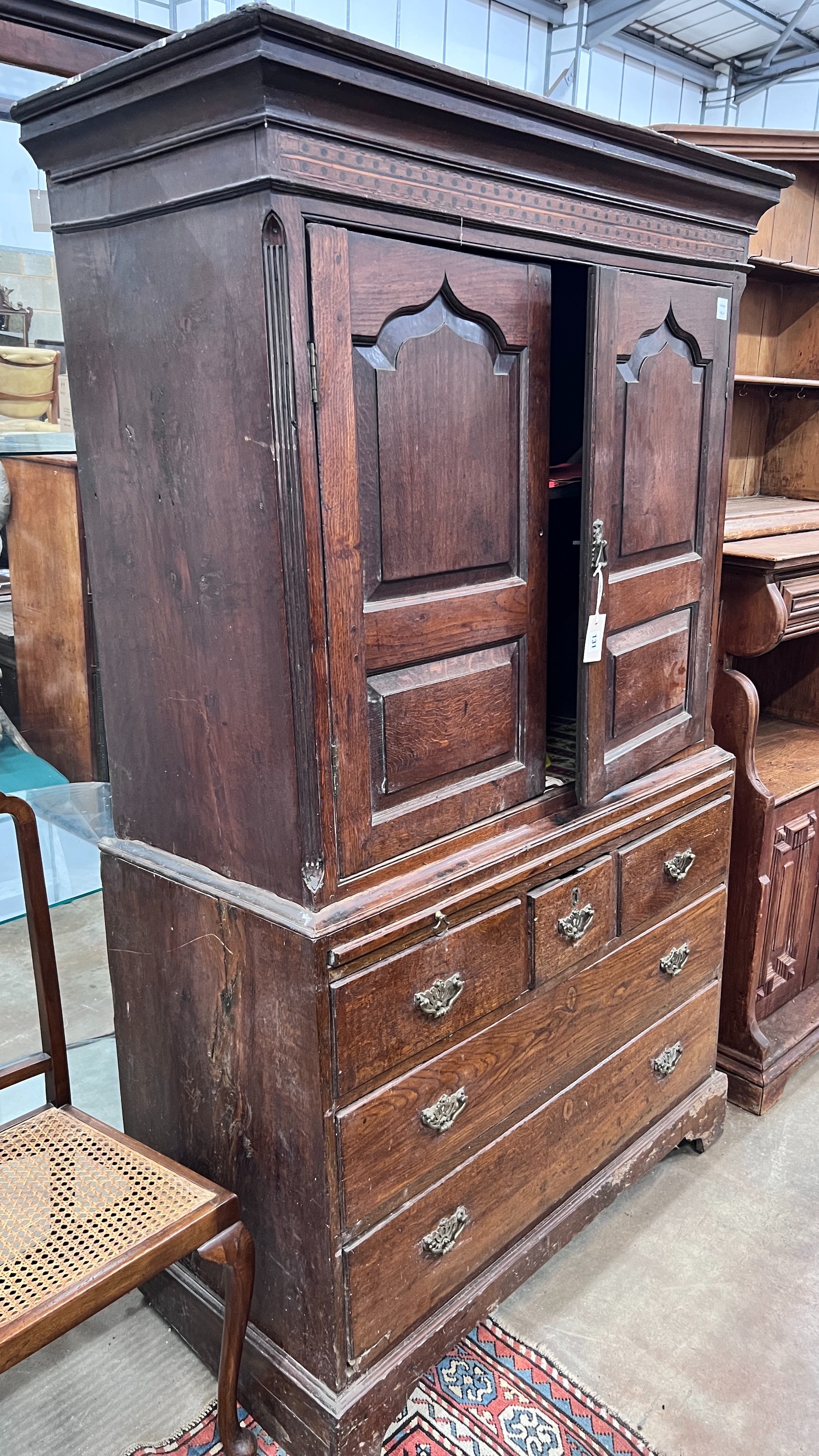 A George III oak press cupboard with two panelled doors over five drawers, width 111cm, depth 53cm, height 186cm *Please note the sale commences at 9am.